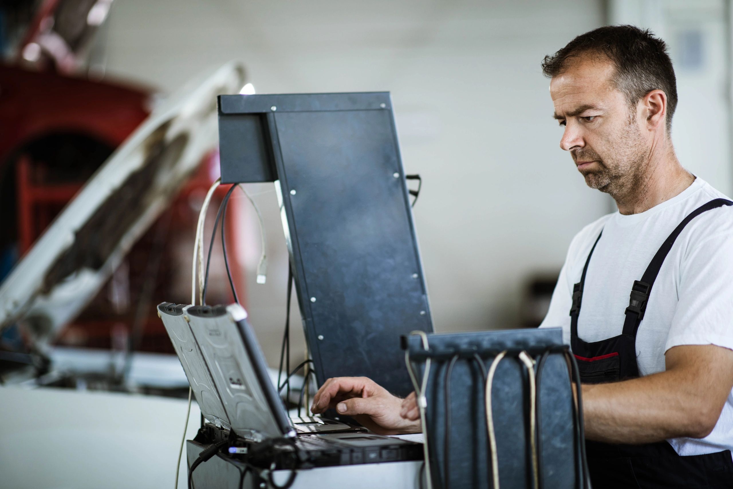 Technician using a laptop for vehicle diagnostics in a repair shop