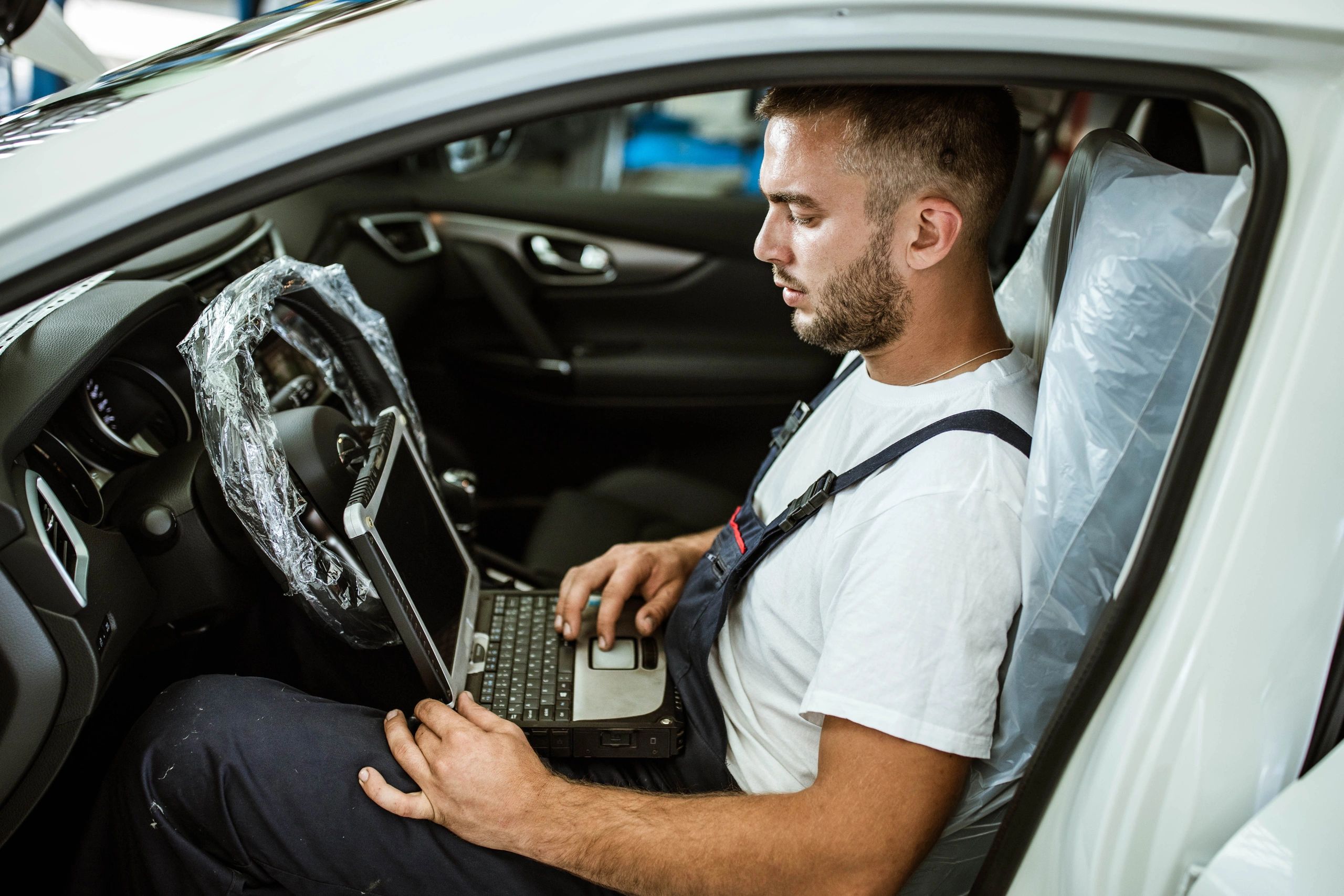 Mechanic using a laptop to test vehicle performance in a workshop