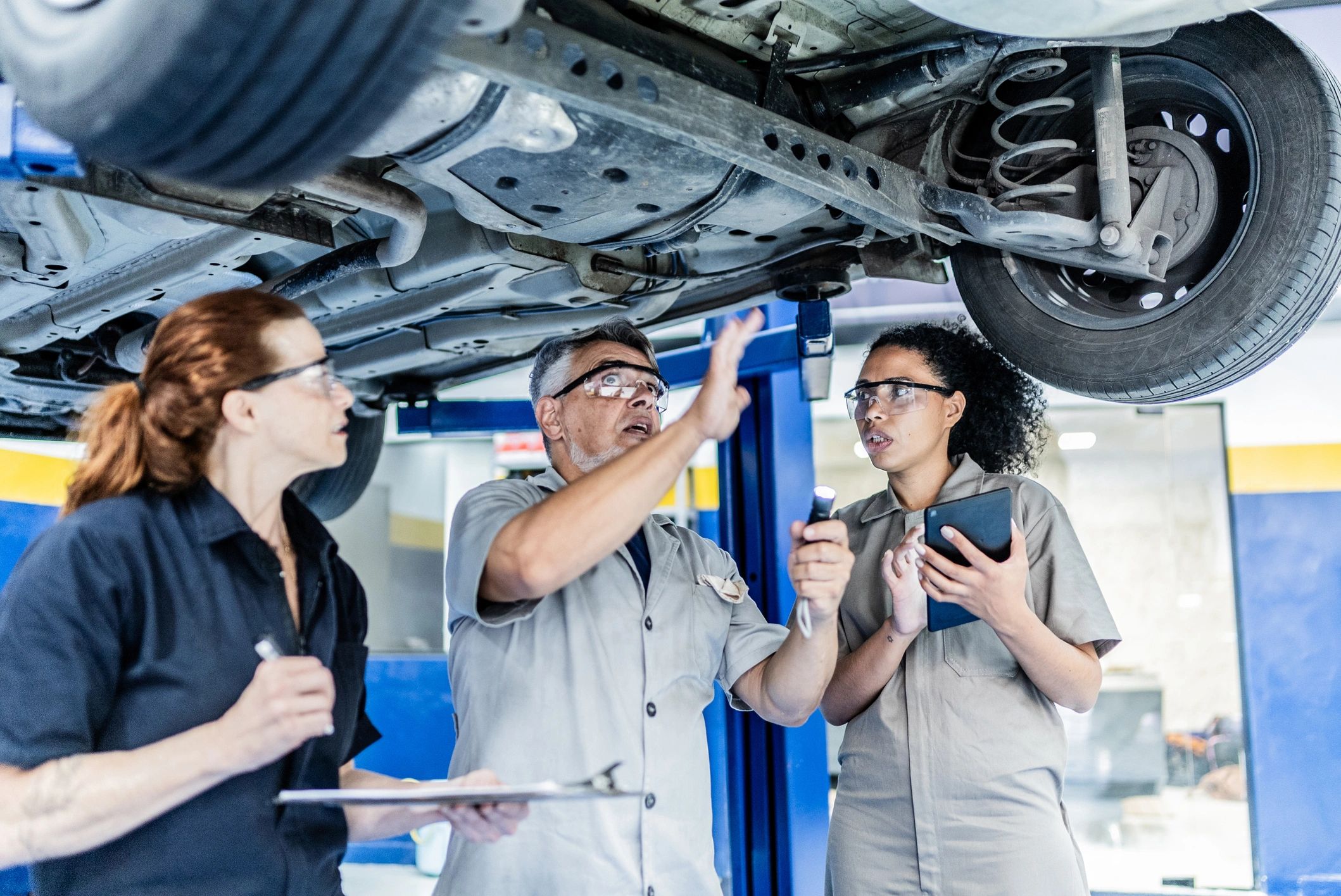 Auto mechanics adjusting a vehicle on a lift