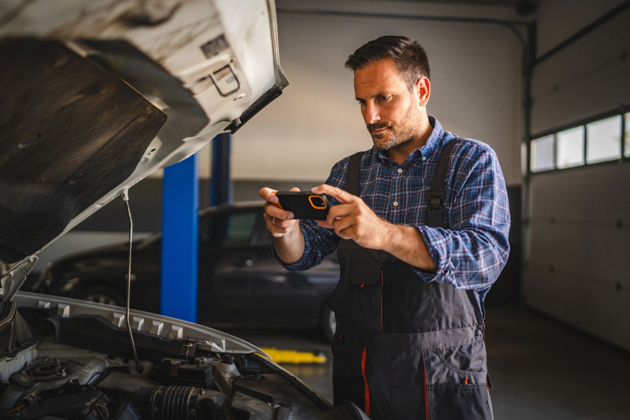 Mechanic photographing an engine bay for diagnostics